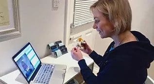 Woman participating in online cooking class via laptop.