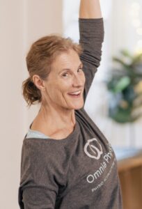 Smiling woman stretching arm at physio session