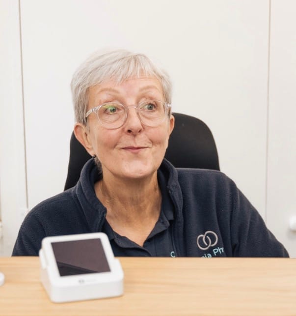 Older woman with glasses at desk with device