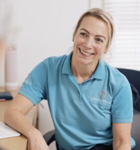 Smiling physiotherapist in blue shirt seated at desk