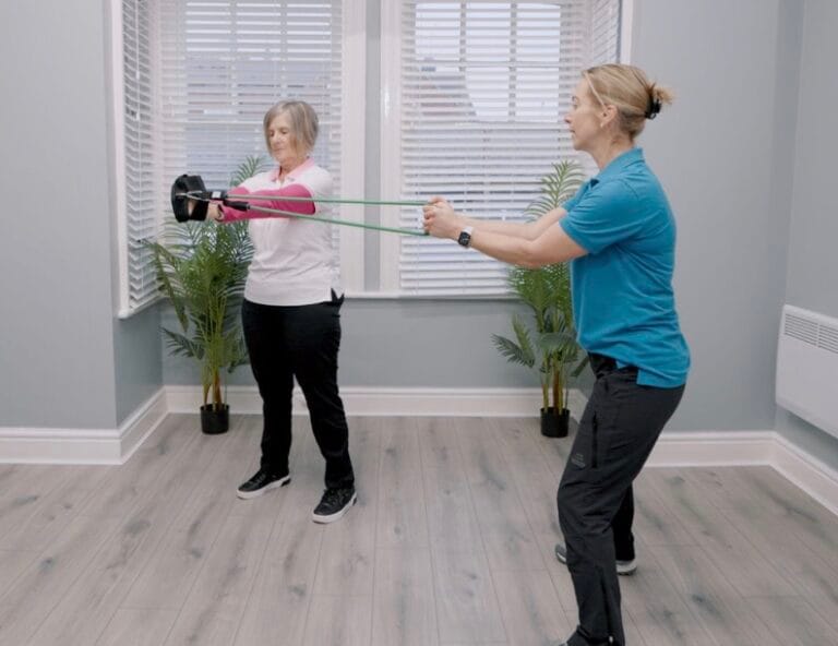 Woman doing resistance band exercise with trainer indoors