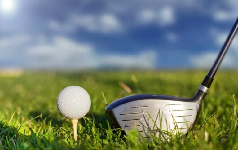 Golf ball on tee beside driver club