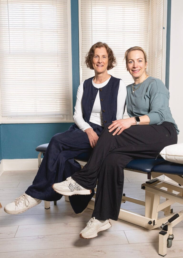 Two women sitting on a treatment table.