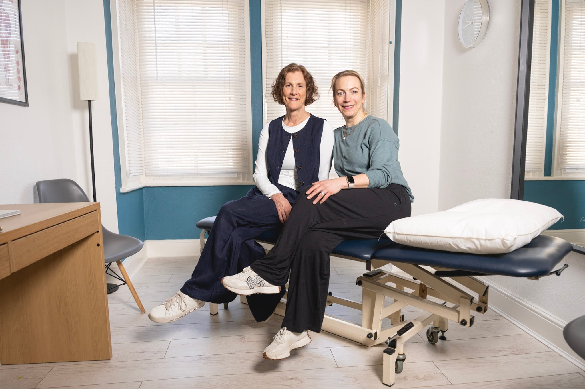 Two women sitting on clinic examination couch smiling