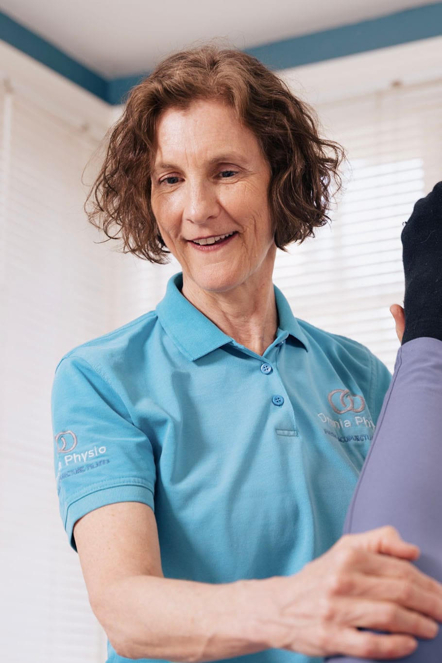 Physiotherapist assisting patient with leg exercise in clinic