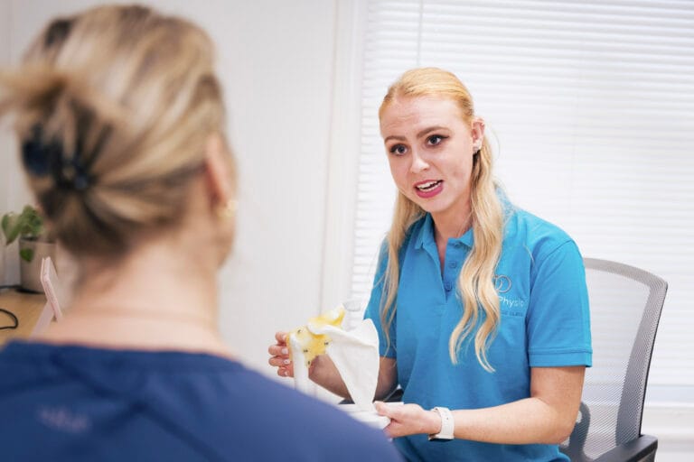 Physiotherapist explaining shoulder model to patient in clinic