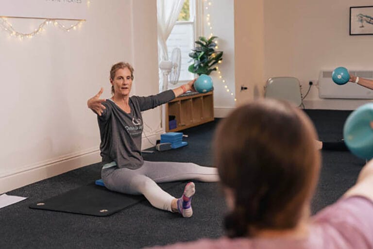 Woman leading Pilates class with exercise balls