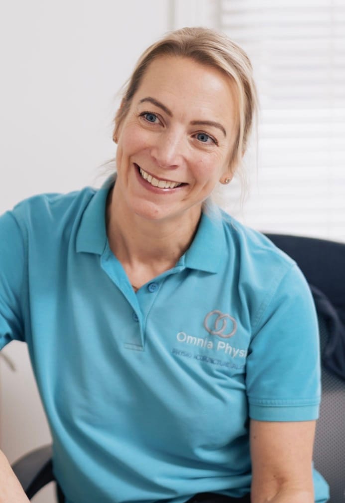 Smiling physiotherapist in teal Omnia Physio polo shirt