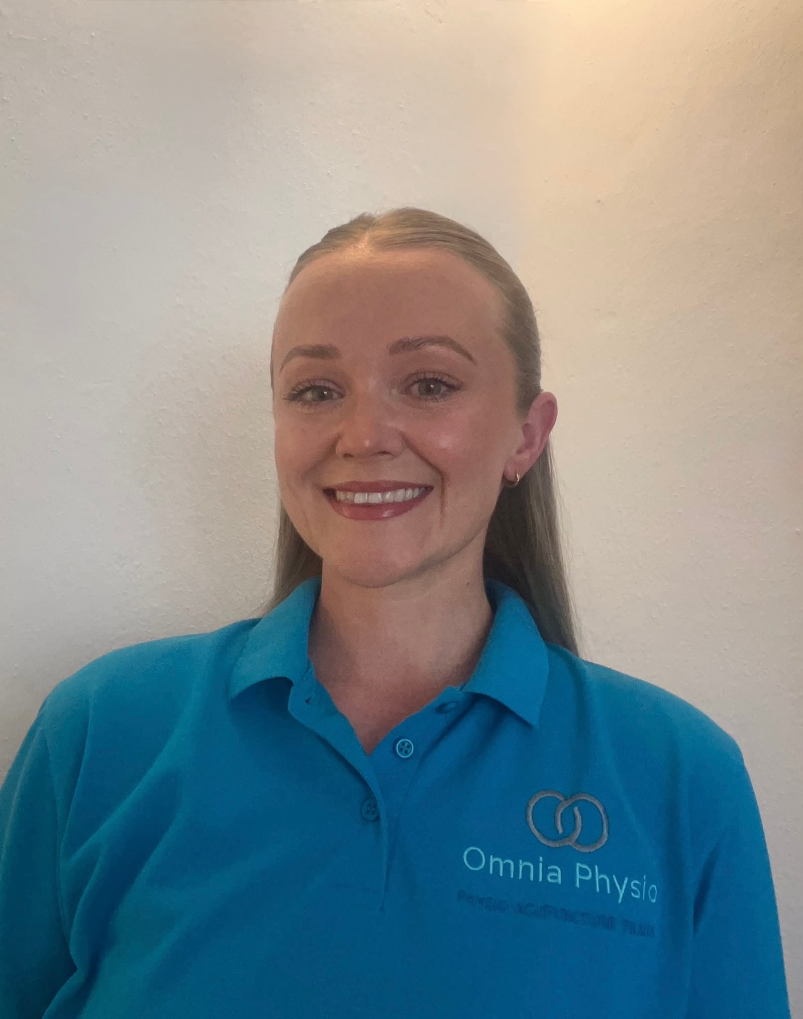 Smiling physiotherapist in teal Omnia Physio polo