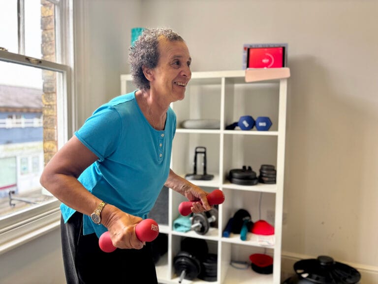 Smiling woman exercising with pink dumbbells in a gym