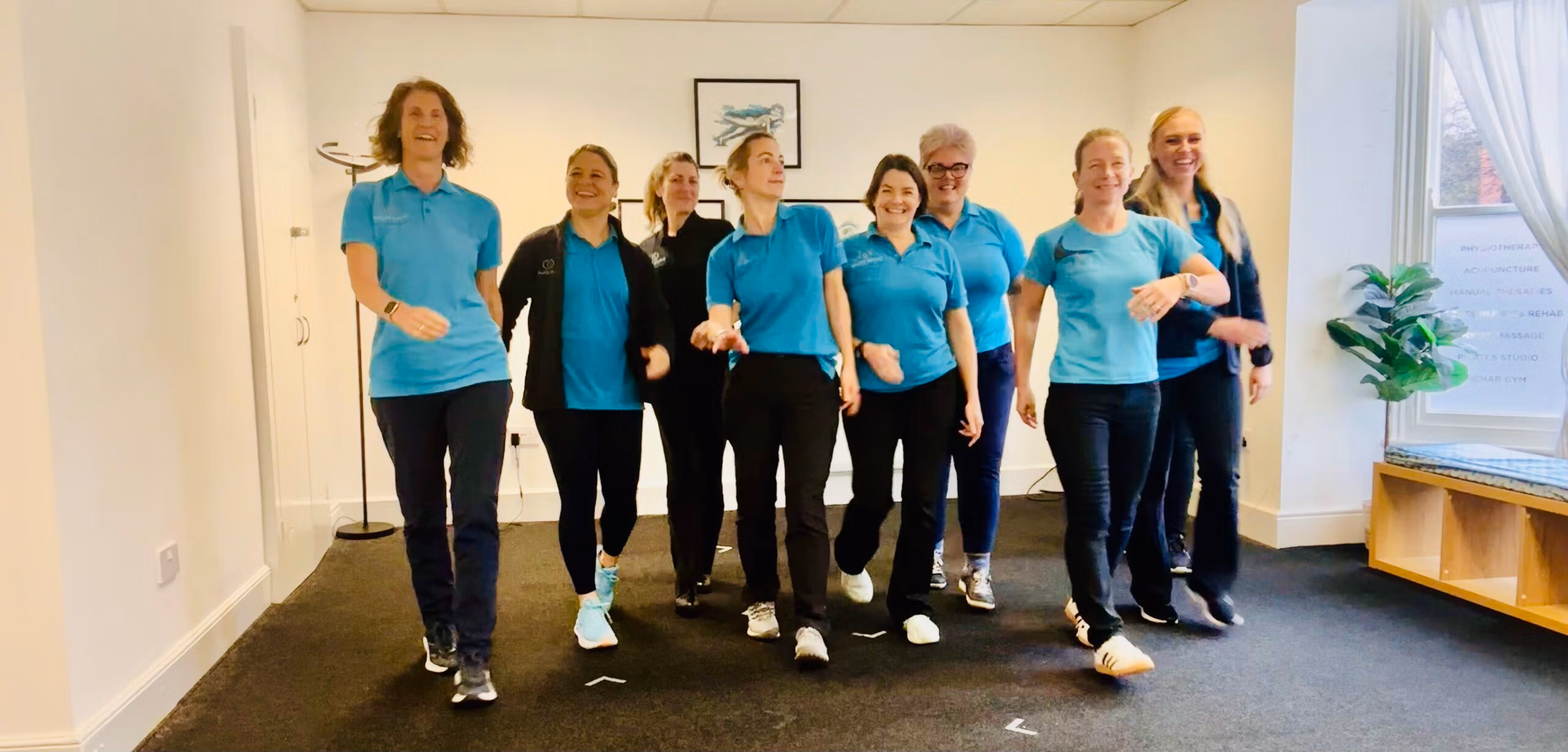 Smiling physiotherapy team walking through a clinic corridor