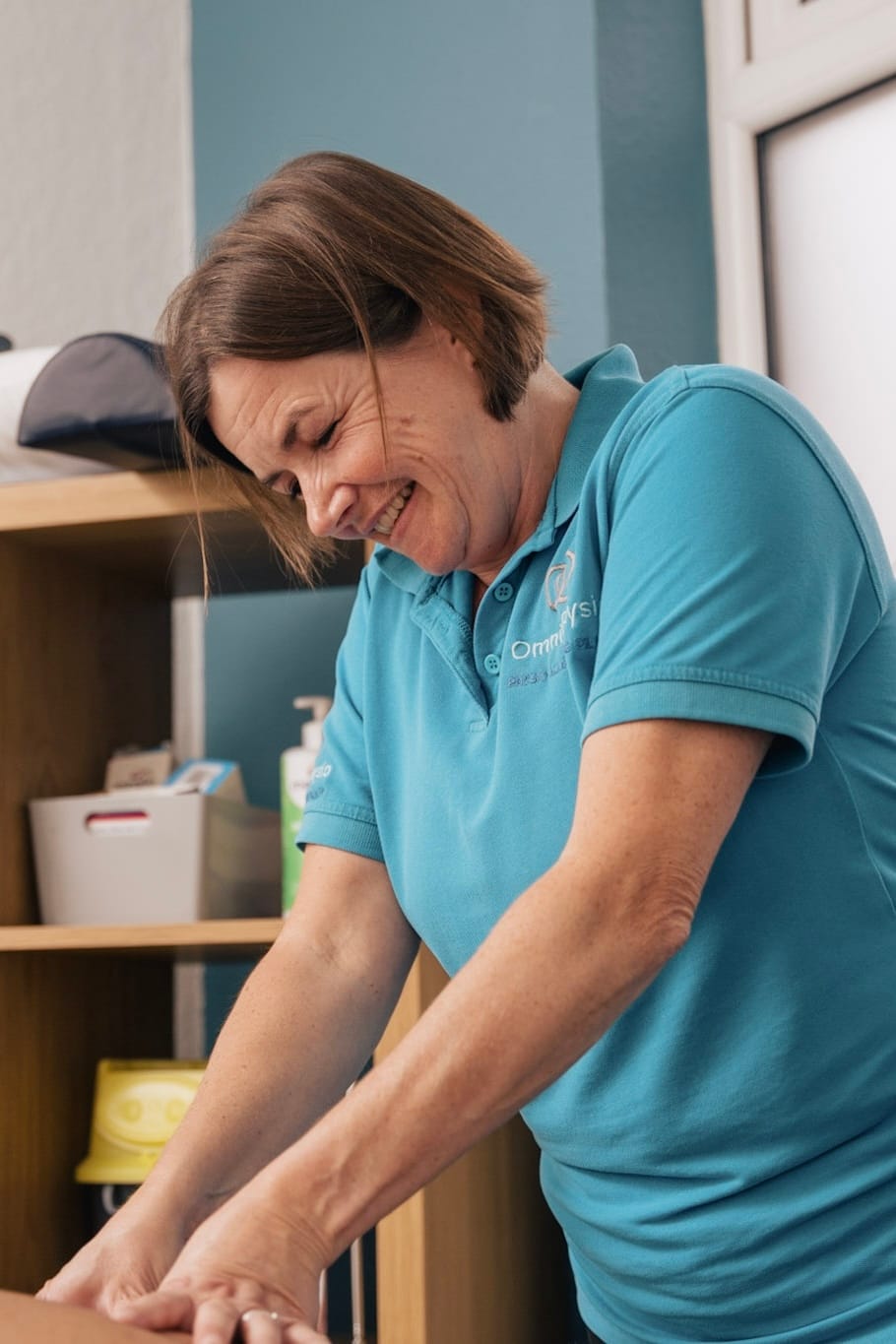 Smiling physiotherapist giving hands-on treatment in a clinic